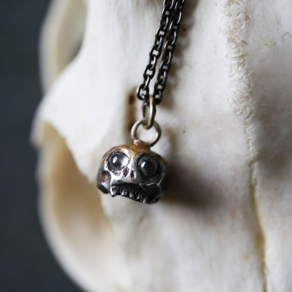 Skull charm with amethyst eyes - Machinations